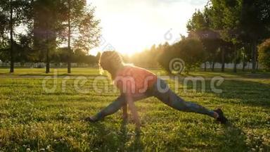 体操女子坐在纵向和横向分裂。 在城市公园里伸展